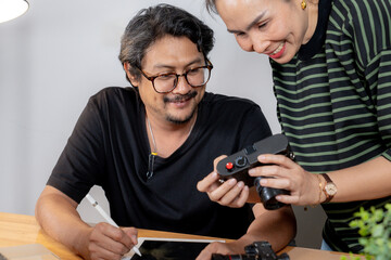 Creative collaboration at home, two photographers editing and discussing their projects together.