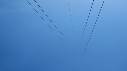 Abstract photo of power lines against a misty blue sky. Perfect for backgrounds or minimalist...