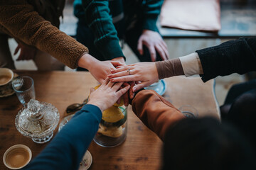 A close-up of a group of people joining hands in a symbolic gesture of teamwork and solidarity....