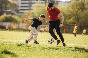 Obraz premium Game of soccer. Father and son are having fun outdoors