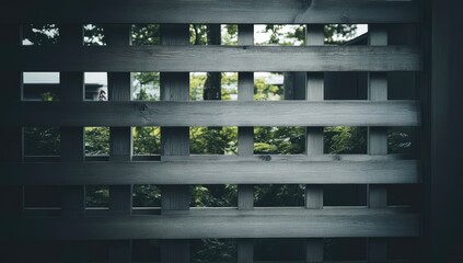 Gray wooden lattice fence with square openings, showcasing greenery beyond