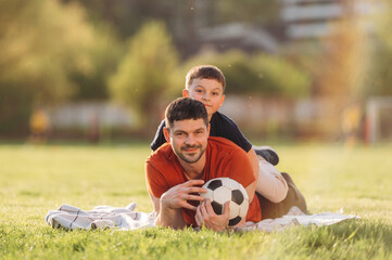 Front view, lying down. Father and son are having fun outdoors