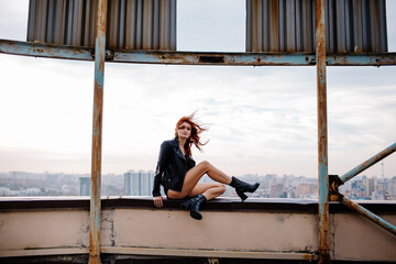 Red-haired girl in shorts and a leather jacket on a rooftop