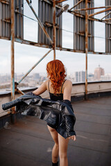 Red-haired girl in shorts and a leather jacket on a rooftop