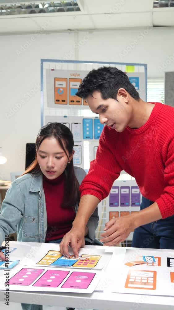 Poster young asian ux/ui designers working together on a new mobile app, analyzing the different screens an