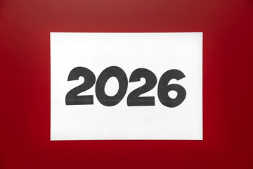 A large white print displaying the number 2026 stands out against a vibrant red background, symbolizing upcoming year and future aspirations, focusing attention on new beginnings
