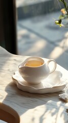 Fototapeta premium Tea Service Still Life in Natural Light White Porcelain Teapot and Saucer on Marble Tabletop Close Up