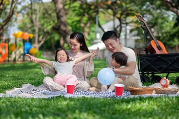 Joyful family enjoying picnic time at the park with kids playing and parents relaxing together.