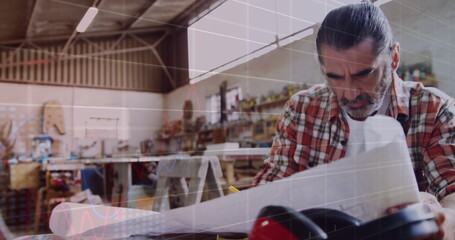 Image of data processing over caucasian male carpenter studying plans in workshop
