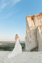 a woman in a white dress, a bride on a mountain with a blue sky. Beautiful nature, freedom, enjoyment of life. High quality photo