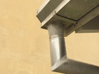 Closeup of a metal gutter with repairs with beige background. Detail of a building.