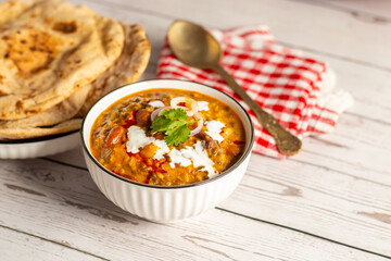 Dal Makhani is a rich, creamy lentil dish made with black lentils, kidney beans, and spices, served with soft, charred tandoori roti for a perfect meal.
