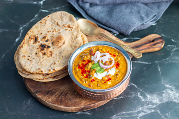 Dal Makhani is a rich, creamy lentil dish made with black lentils, kidney beans, and spices, served with soft, charred tandoori roti for a perfect meal.
