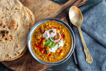 Dal Makhani is a rich, creamy lentil dish made with black lentils, kidney beans, and spices, served with soft, charred tandoori roti for a perfect meal.
