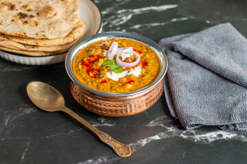 Dal Makhani is a rich, creamy lentil dish made with black lentils, kidney beans, and spices, served with soft, charred tandoori roti for a perfect meal.
