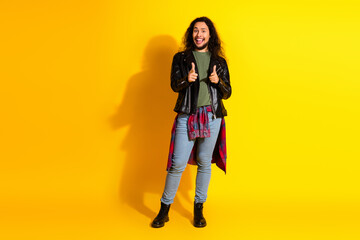 Young man in casual trendy outfit posing confidently against bright yellow background with...