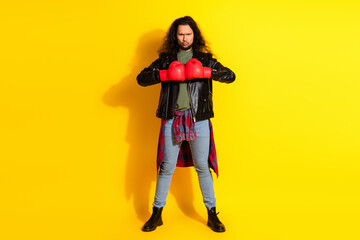 Stylish young man with boxing gloves posing confidently against a vibrant yellow background...
