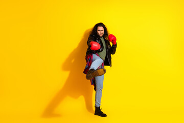 Young man in boxing gloves striking a confident pose against a bright yellow background in trendy...