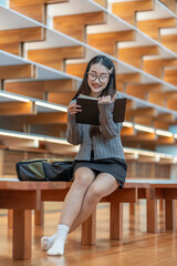 Fototapeta premium portrait happy female college student enjoy reading a book alone in the room at reading area in campus,concept education,academic