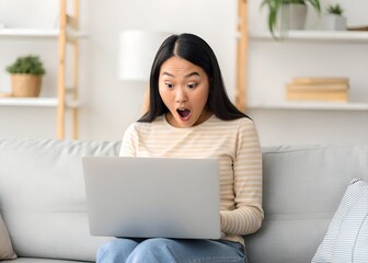 Naklejka premium Some Problem. Surprised and shocked asian lady watching something unbelievable and unexpected on computer, sitting on couch at home, copy space. Young woman with open mouth using laptop
