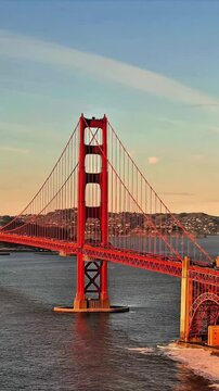 Drone vertical view of Golden Gate Bridge with traffic over blue water at sunset