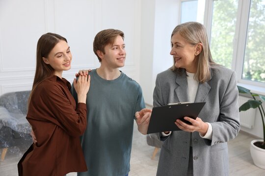 Smiling real estate agent with clipboard working with couple at home