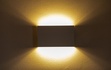 Modern wall lamp illuminating textured wall with warm light