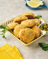Fish cutlets from white sea fish in golden breading in a ceramic plate on a light concrete background. Recipes fish, seafood.