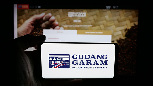 Stuttgart, Germany - 05-02-2025: Person holding cellphone with logo of Indonesian tobacco company Gudang Garam on screen in front of webpage. Focus on phone display.