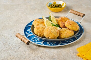Fish cutlets from white sea fish in golden breading in a ceramic plate on a light concrete background. Recipes fish, seafood.