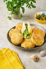 Fish cutlets from white sea fish in golden breading in a ceramic plate on a light concrete background. Recipes fish, seafood.