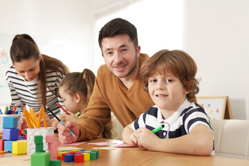Fototapeta premium Cute boy and teacher at desk during lesson in school