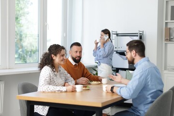 Colleagues eating and chatting during lunch break in office