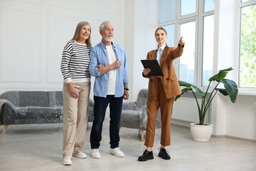 Fototapeta premium Smiling real estate agent showing apartment to couple indoors