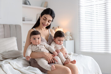 Bedtime. Mother with her cute little babies on bed at home