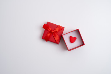 Red gift box with heart on white close-up on light background.Minimal Valentine's Day or love concept.
