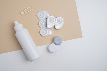 Contact lenses, case and bottle with solution and eye drops on white background. Eye health and care, vision, ophthalmology concept, close-up 