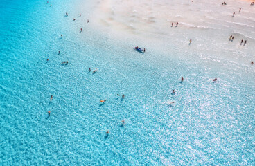 Aerial view of clear blue sea with swimming people. Top view from drone of beach with white sand, blue transparent water on sunny day. Summer in La Pelosa beach, Sardinia, Italy. Tropical landscape