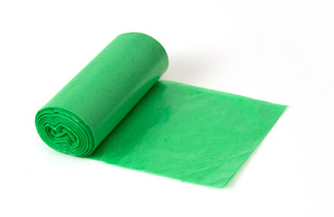 Green plastic garbage bag roll partially unrolled on white background, household waste bag for cleaning or trash disposal.