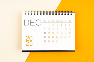 Desk calendar for December 2025 year on yellow background, Flat lay.