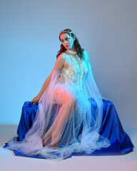 Fantasy studio portrait of a red-haired mermaid faery model wearing a white pearl gown, fairytale...