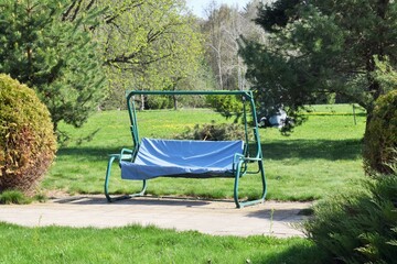 Summer landscape. A rocking sofa is installed in the park
