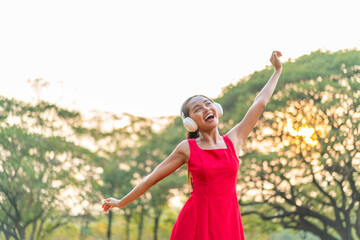 Asian Woman in a Red Dress Dancing to the Rhythm While Listening to Music in the Park
