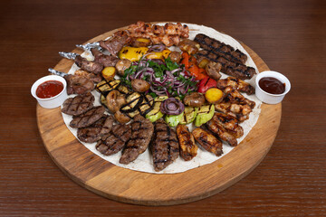 Cold cuts with beef, lamb, chicken with eggplant, red onion, barbecue sauce and adjika on the table in the restaurant on a wooden stand