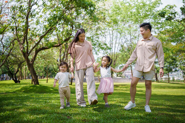 Fototapeta premium Carefree family enjoying a walk together in a green park on a sunny day.