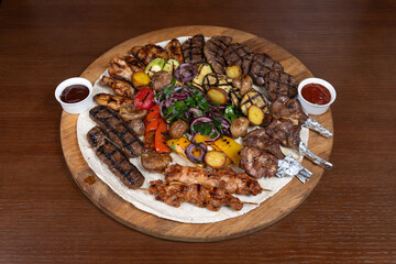 Cold cuts with beef, lamb, chicken with eggplant, red onion, barbecue sauce and adjika on the table in the restaurant on a wooden stand