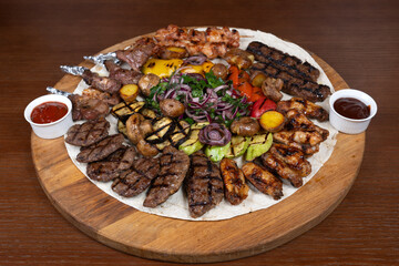 Cold cuts with beef, lamb, chicken with eggplant, red onion, barbecue sauce and adjika on the table in the restaurant on a wooden stand