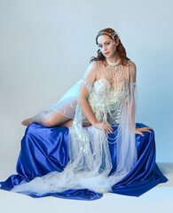 Fantasy studio portrait of a red-haired mermaid faery model wearing a white pearl gown, fairytale...