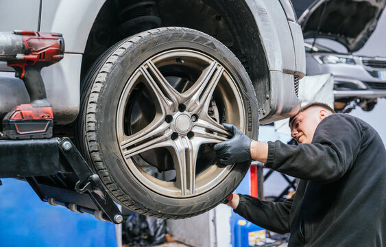 Mechanic working on elevated car wheel in professional auto repair workshop
