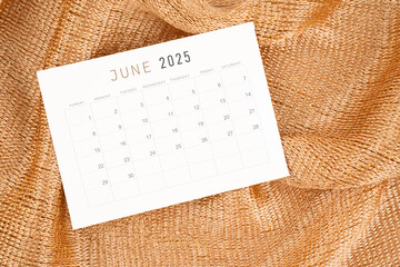 June 2025 calendar card on golden color textile.